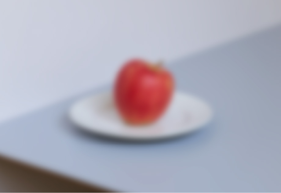 「コントランス低下」体験メガネの見え方。ぼんやりと皿に置かれた赤いリンゴが見える。