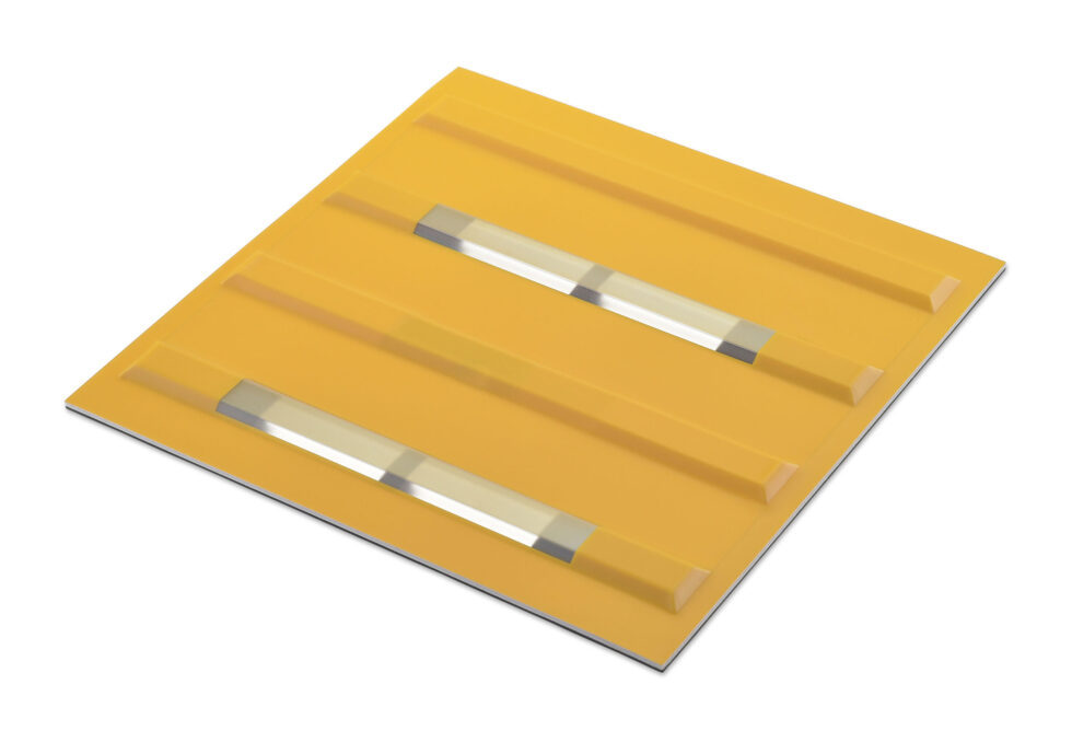 薄型ソーラービーコン内蔵点字ブロックを、斜め上から見た写真。誘導ブロックの突起部分に、細長いソーラーパネルが2個内蔵されているのが見える。