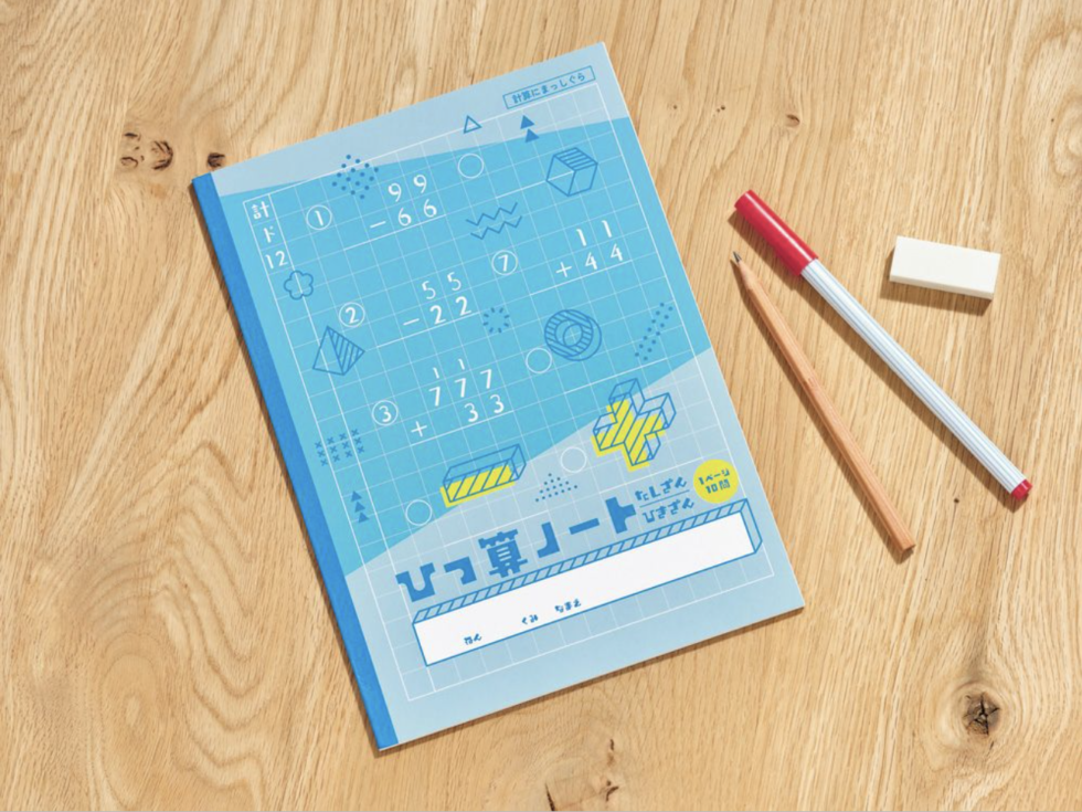 テーブルにひっ算ノートとペン、消しゴムが置かれている。ノートの水色の表紙には、ひっ算式などが描かれている。