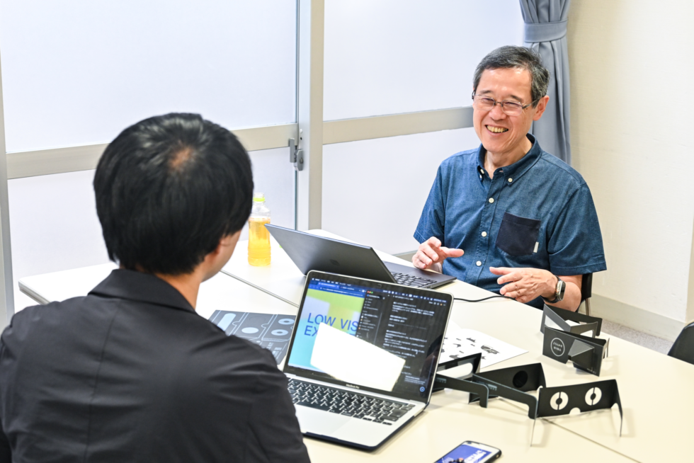 タキザワの対面に座り、笑顔で話す山本さん