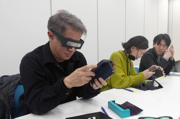 弱視体験用メガネをかけ、スマホを見る参加者の写真