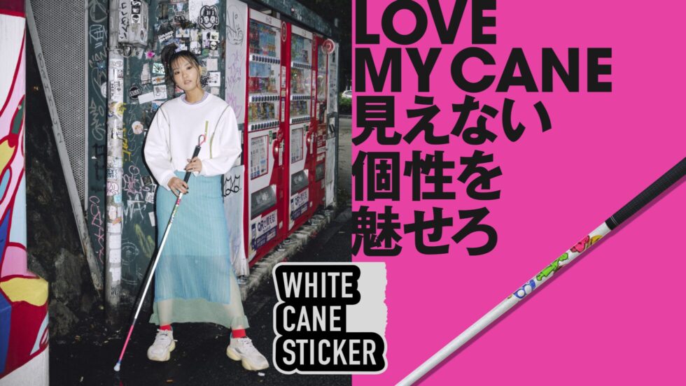 渋谷のストリートでステッカーが貼られた白杖をかっこよく持つ、視覚障害のモデル女性の写真。
