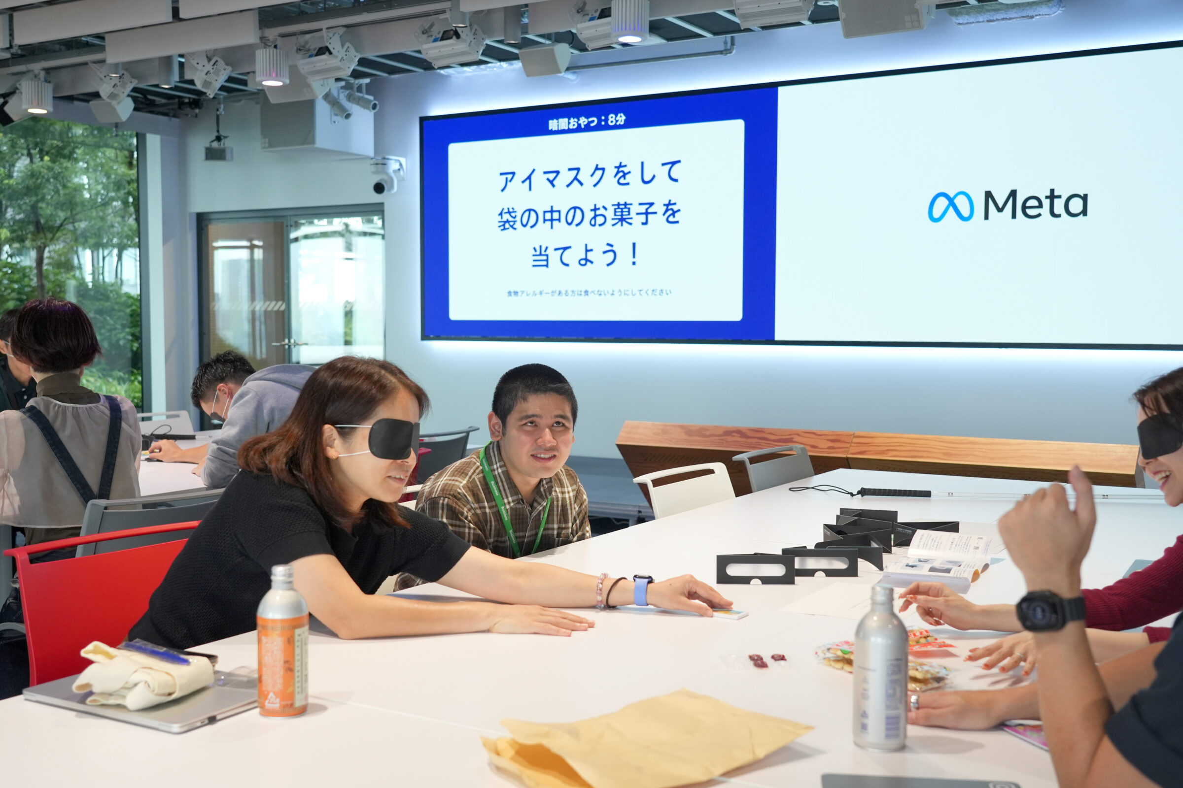 参加者がアイマスクを着け、「袋の中のお菓子を当てよう！」という体験に取り組んでいる。