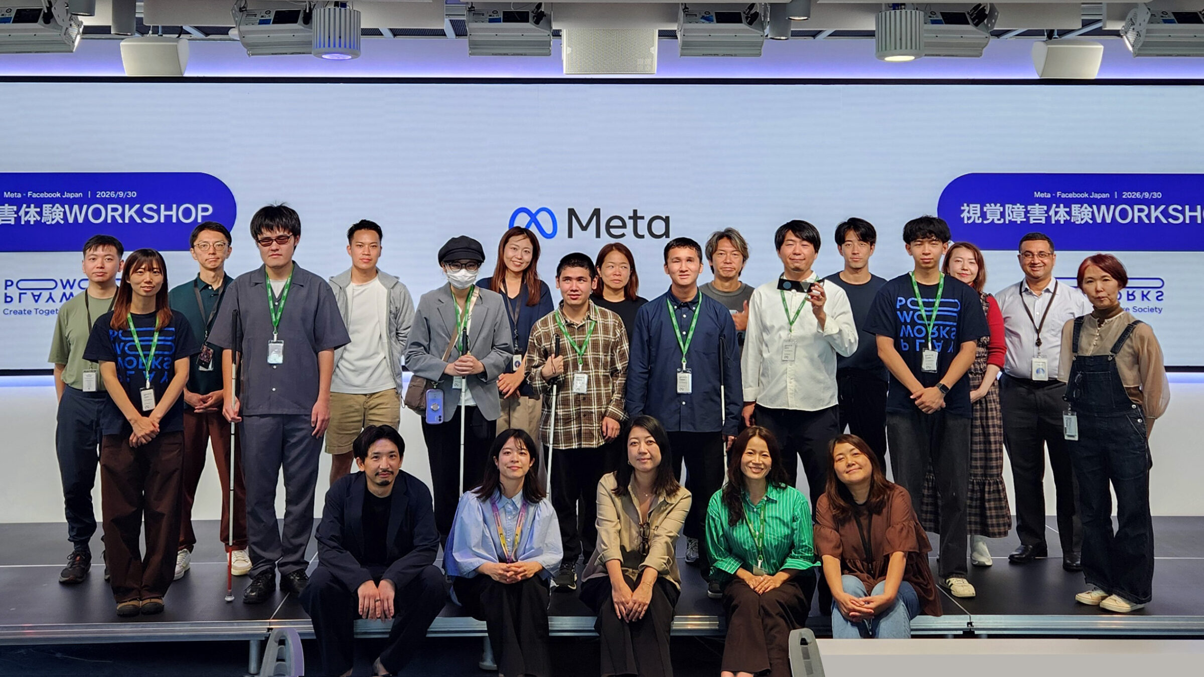 Metaオフィスで開催された「視覚障害体験WORKSHOP」の参加者による集合写真。視覚障害のあるリードユーザーやMeta、PLAYWORKSのメンバーなどが、Metaのロゴとワークショップ名が映る大型スクリーンの前に並んでいる。